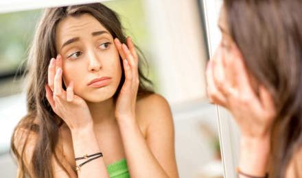 Ein Teenager überprüft von einer Allergie geschwollene Augen in einem Spiegel
