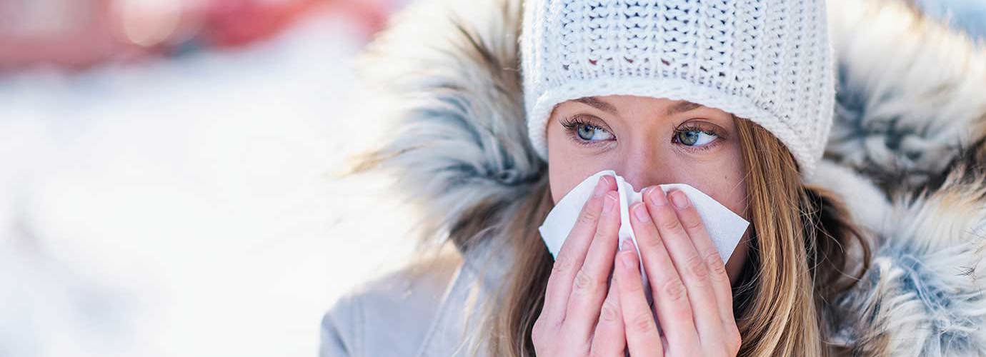 Eine Frau im Schnee schneuzt sich