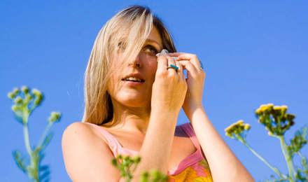 Eine Frau zwischen Blumen leidet an einer Pollenallergie