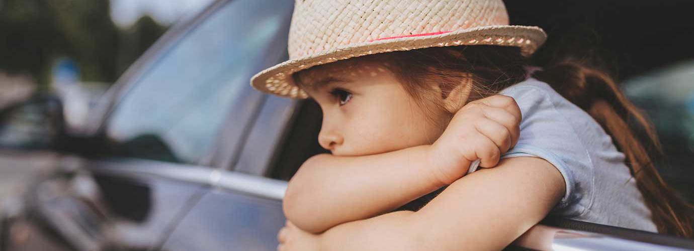 Ein Kind, dem beim Autofarhen übel geworden ist lehnt sich aus dem Autofenster