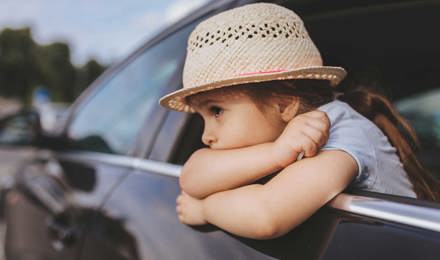 Ein Kind, dem beim Autofarhen übel geworden ist lehnt sich aus dem Autofenster