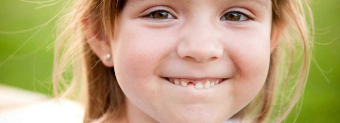 Een jong meisje lacht en laat het gat tussen haar tanden zien, waar haar melktandje net nog kan zijn geweest