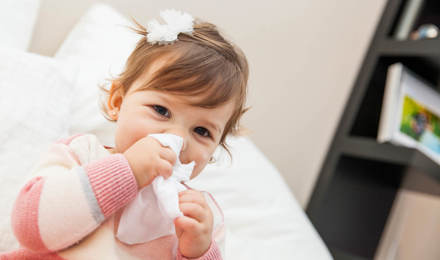 Klein meisje veegt haar neus af met een tissue