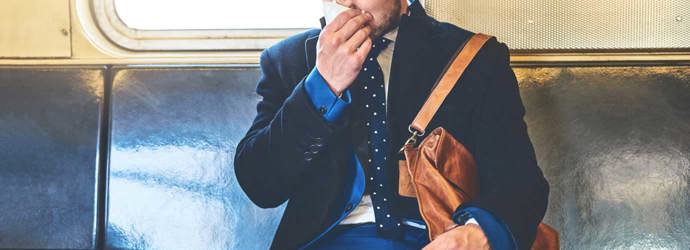 Een man draagt een pak in een treinwagon en snuit zijn neus