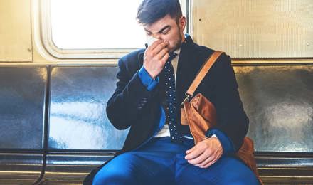 Een man draagt ​​een pak in een treinwagon en snuit zijn neus