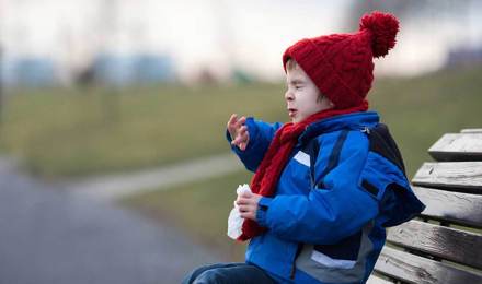 Ein Kind niest auf einer Parkbank im Winter