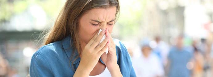 Eine Frau mit Erkältung im Sommer putzt sich die Nase