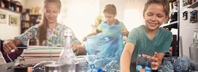 Drei Kinder lernen verschiedenes Plastik und Möglichkeiten zum Recycling kennen, indem sie es sich in der Küche ansehen