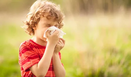 Een jongen met een pollenallergie snuit zijn neus buiten in een veld