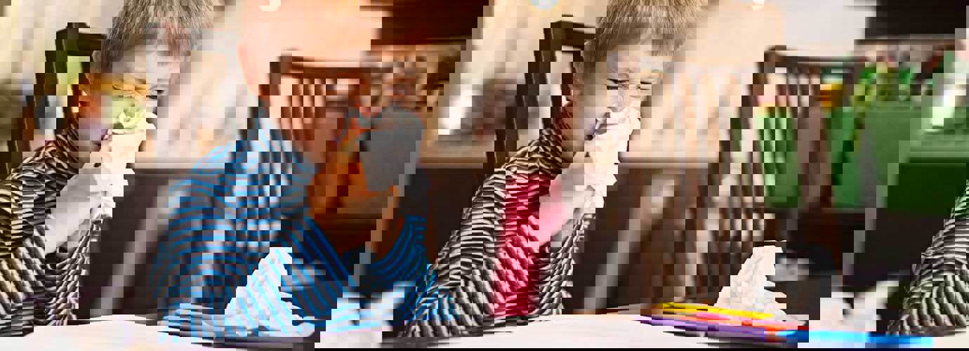 Een kleine jongen snuit zijn neus terwijl hij aan tafel zit met gebruikte tissues om hem heen