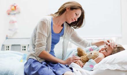 Een moeder verzorgt haar dochter in bed met een kinderverkoudheid