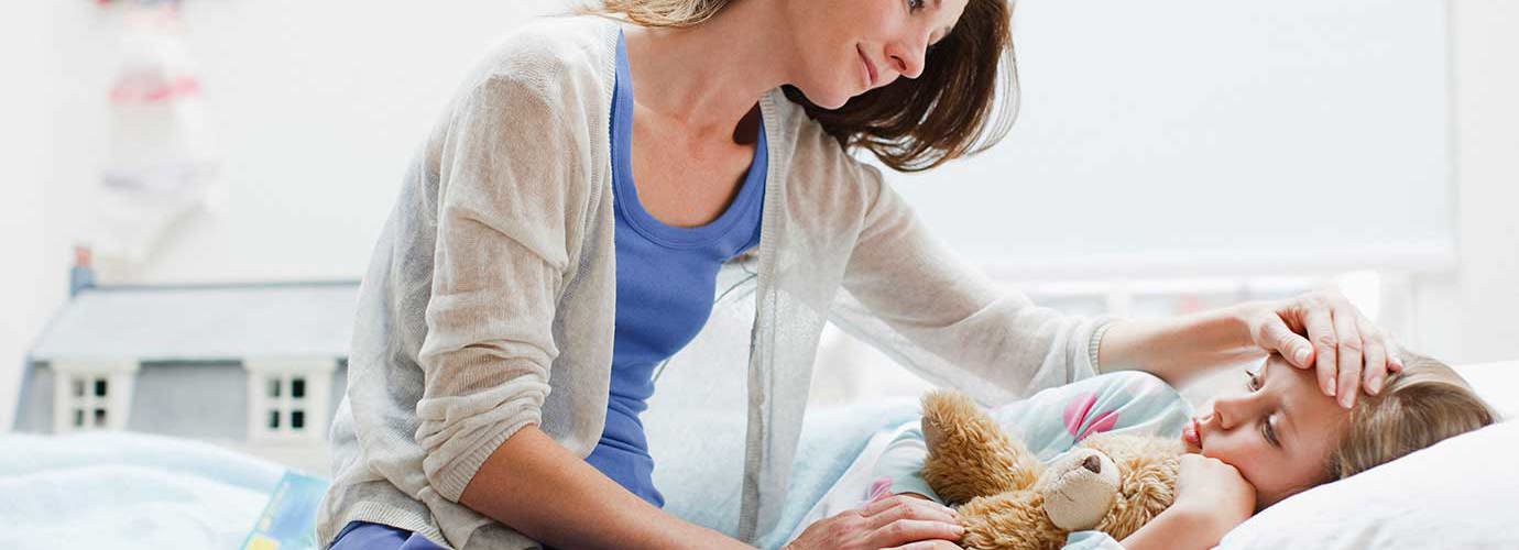 Een moeder verzorgt haar dochter in bed met een kinderverkoudheid