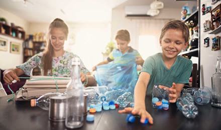 Drei Kinder lernen verschiedenes Plastik und Möglichkeiten zum Recycling kennen, indem sie es sich in der Küche ansehen