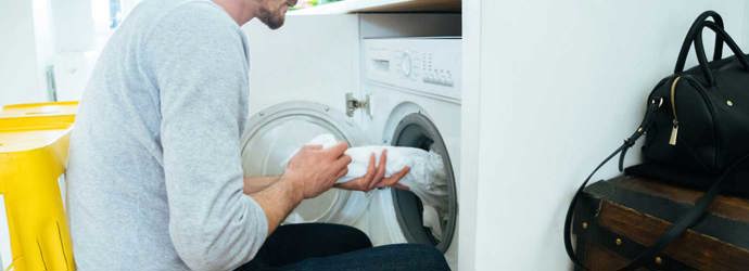 Ein Mann legt Kleidung in eine Waschmaschine